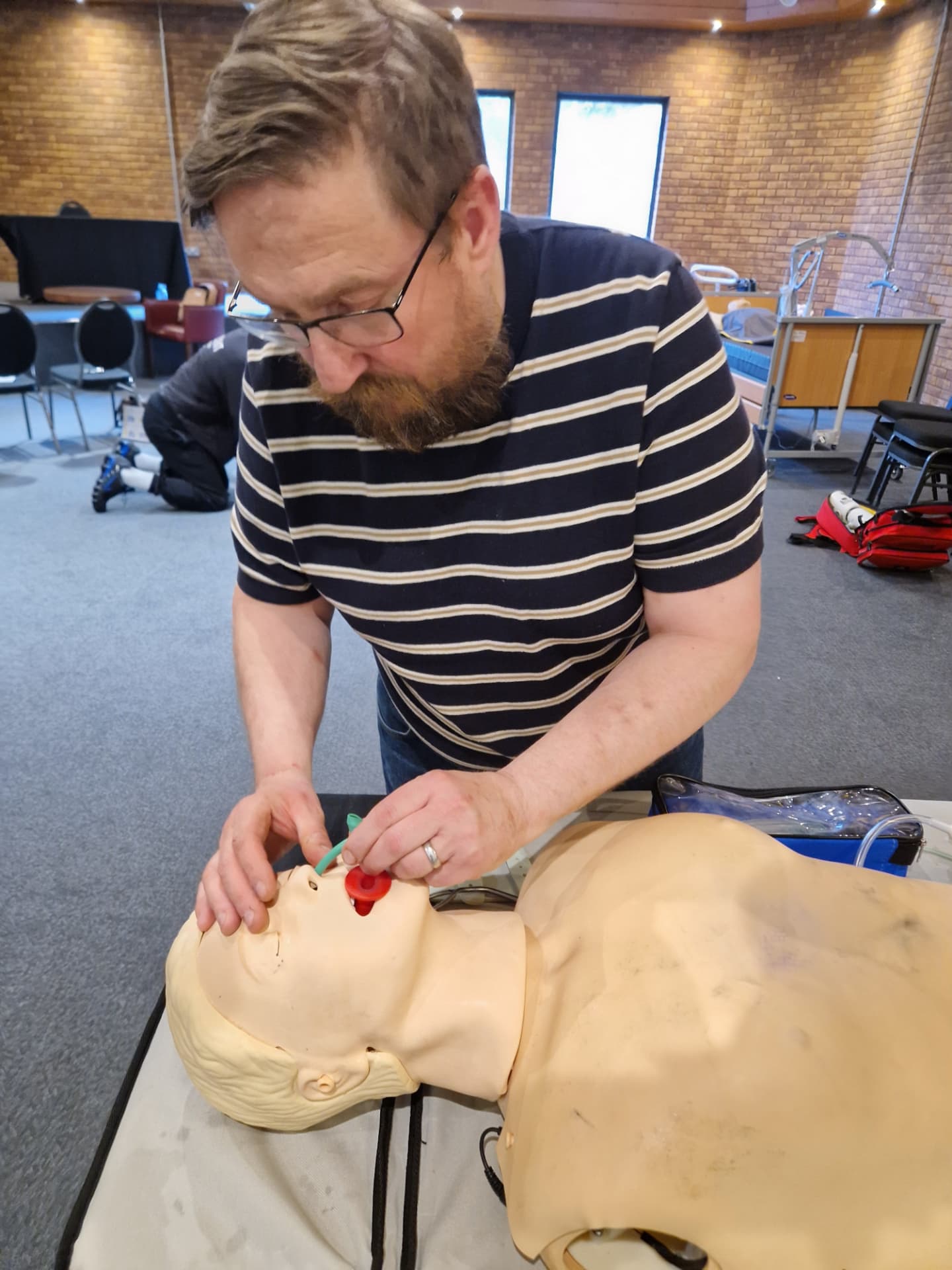 A trainer practising airway management on a training manikin during a first aid course